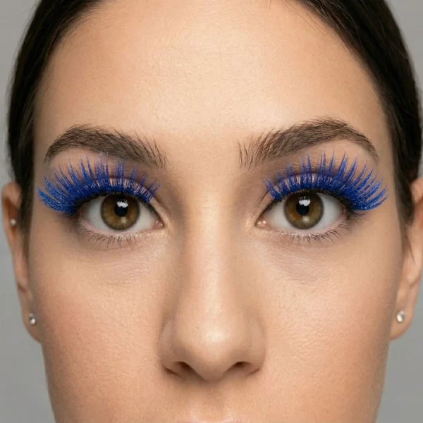 Primer plano frontal de los ojos marrones de una mujer usando pestañas postizas tupidas y largas de color azul eléctrico vibrante con purpurina.