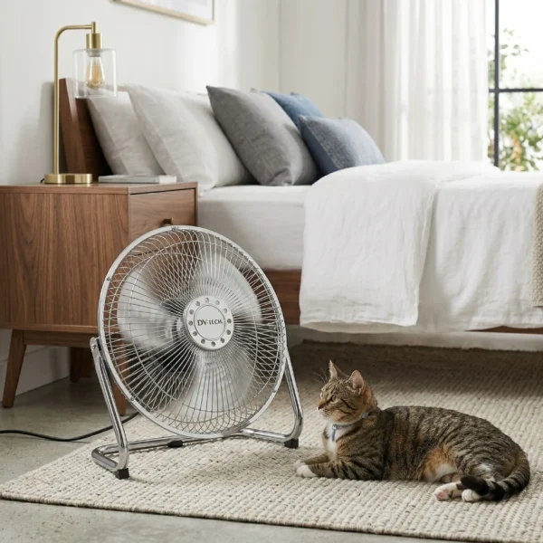 Gato descansando frente a un ventilador de suelo metálico industrial DV-TECH en un dormitorio iluminado y acogedor.