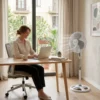 Mujer trabajando con laptop en escritorio refrescada por un ventilador de pie DVTECH, ideal para mantener la concentración.