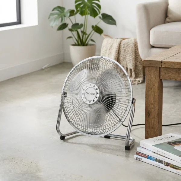 Ventilador de suelo metálico cromado DV-TECH con 3 velocidades en un salón moderno con suelo de cemento y plantas.