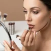 Modelo femenina aplicando barra de maquillaje marrón para definir el contorno de labios y demostrando la suavidad del trazo en el rostro.