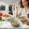 Mujer utilizando la batidora de mano Kiwi para batir una crema de champiñones en un bol sobre encimera de mármol.