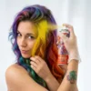Una persona aplicando spray de color amarillo intenso en un mechón de cabello teñido de colores, mostrando la cobertura inmediata del producto.