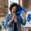 Mujer con cabello rizado aplicando spray de color azul para crear un look de fantasía temporal de forma fácil.