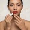 Primer plano de mujer aplicando barra de maquillaje roja en los labios mostrando la alta pigmentación y precisión del crayón.