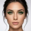 Primer plano de modelo con maquillaje de ojos resaltado por pestañas postizas verdes de varias capas y volumen extremo.