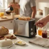 Primer plano de la tostadora calidad-precio marca Kiwi en acabado cromo, mostrando su capacidad para tostar pan artesanal grueso cortado a mano, con una persona sirviendo café al fondo.