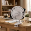 Mini ventilador blanco DVtec de 6 pulgadas sujeto a un escritorio de madera junto a una laptop, ideal para refrescar el área de trabajo sin ruido.