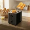 Tostadora de pan negra de 700W marca ExtraHouse con dos rebanadas de pan tostado saltando mediante el sistema de rebote automático.