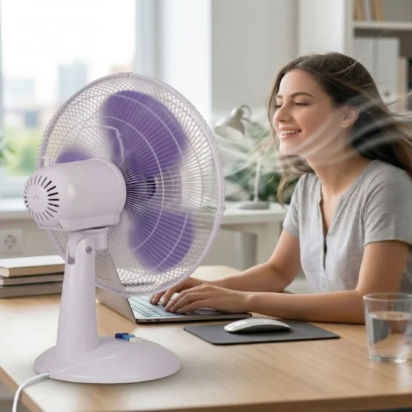 Mujer trabajando con laptop usando un ventilador de escritorio compacto DVTECH para mantener la frescura durante el teletrabajo.