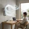 Hombre trabajando en escritorio con laptop mientras utiliza un ventilador de pared DVTECH para ahorrar espacio y mantener el ambiente fresco.