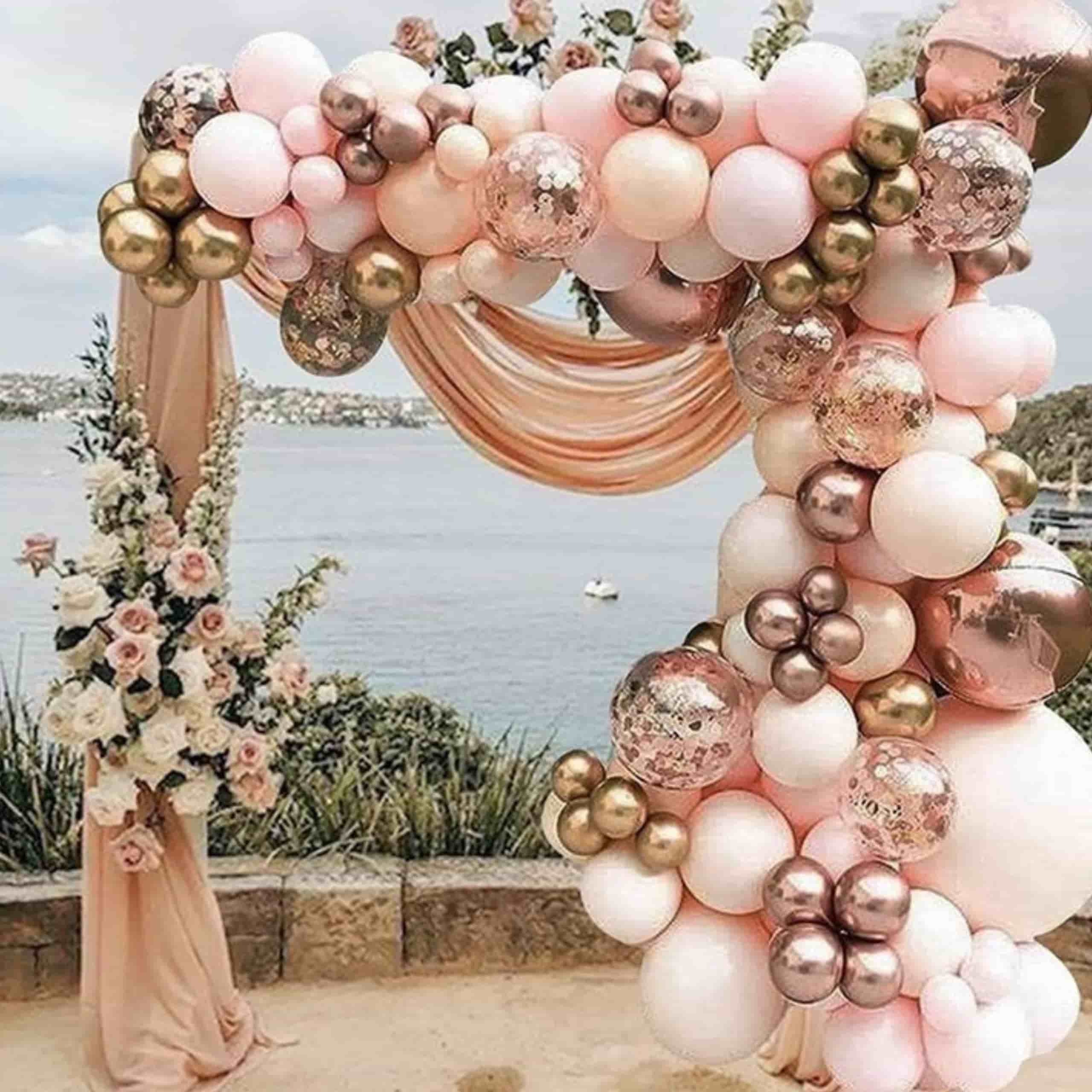Globos oro rosa y dorado en decoración de playa Globos oro rosa y dorado decorando una celebración en la playa con fondo de mar y arena