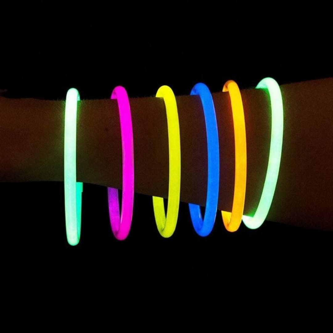 Mano con pulseras luminosas Glow Elite encendidas mostrando colores brillantes en ambiente nocturno