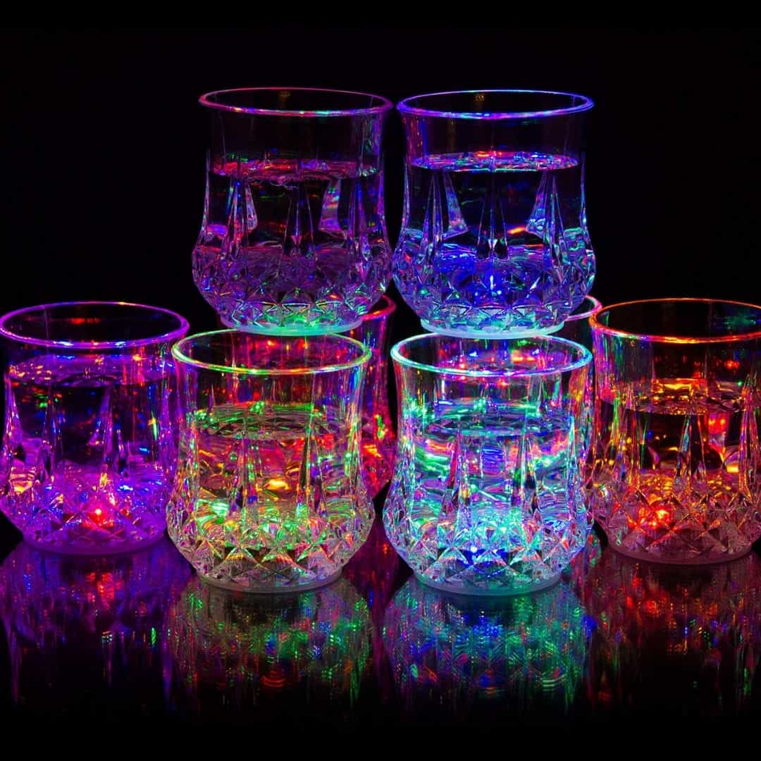 Docena de vasos LED encendidos en diferentes colores Doce vasos LED luminosos encendidos mostrando una amplia gama de colores brillantes en la oscuridad