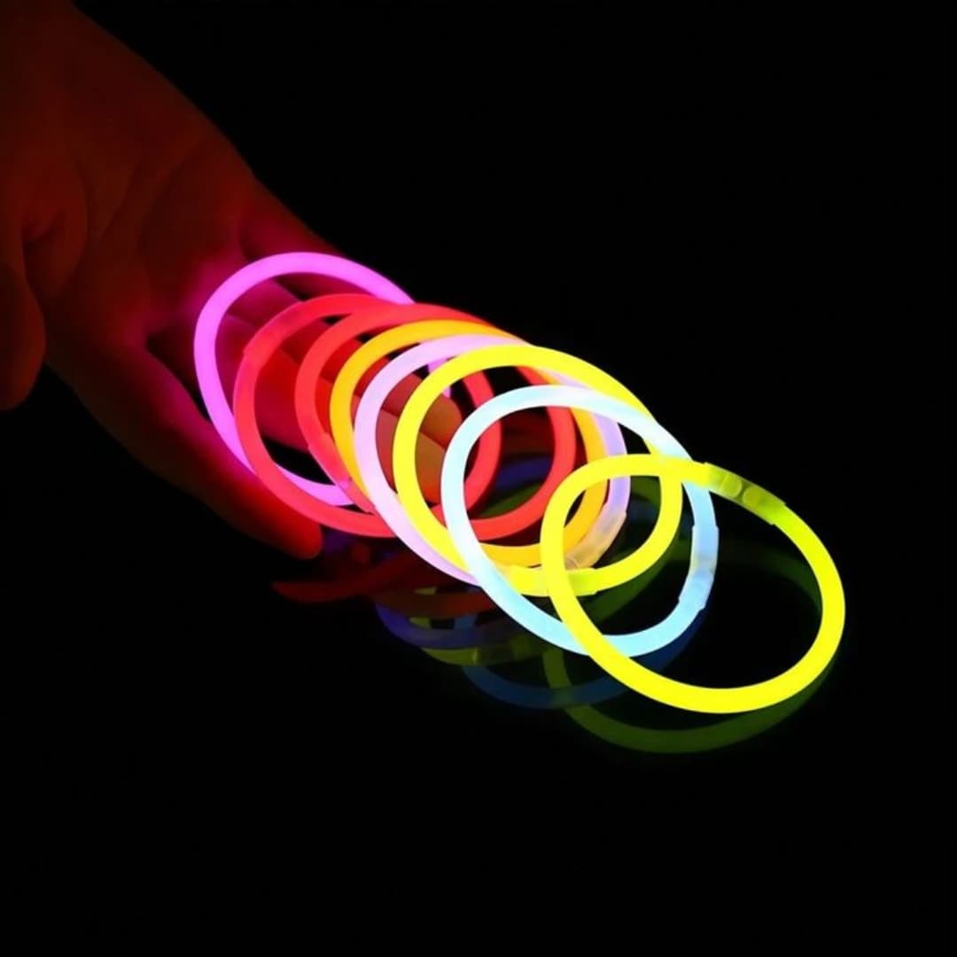 Pulseras fluorescentes Lumi Flex encendidas sobre una mesa en ambiente nocturno durante una fiesta