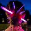 Chica usando pulseras luminosas GlowMaster Pro encendidas como accesorios en el pelo durante una fiesta nocturna