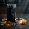 Molino para Especias, Chiles y Semillas Molinillo eléctrico multifunción rodeado de pimienta, canela, cardamomo y granos de café, demostrando su versatilidad para condimentos.
