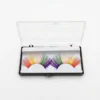 Pestañas Arcoíris en Estuche Premium Pestañas postizas arcoíris de colores vibrantes en su caja de almacenamiento transparente sobre fondo blanco profesional.
