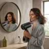 Cómo usar un secador iónico profesional en casa Mujer usando un secador de pelo profesional de 2000W frente al espejo para obtener un acabado de salón con tecnología iónica.